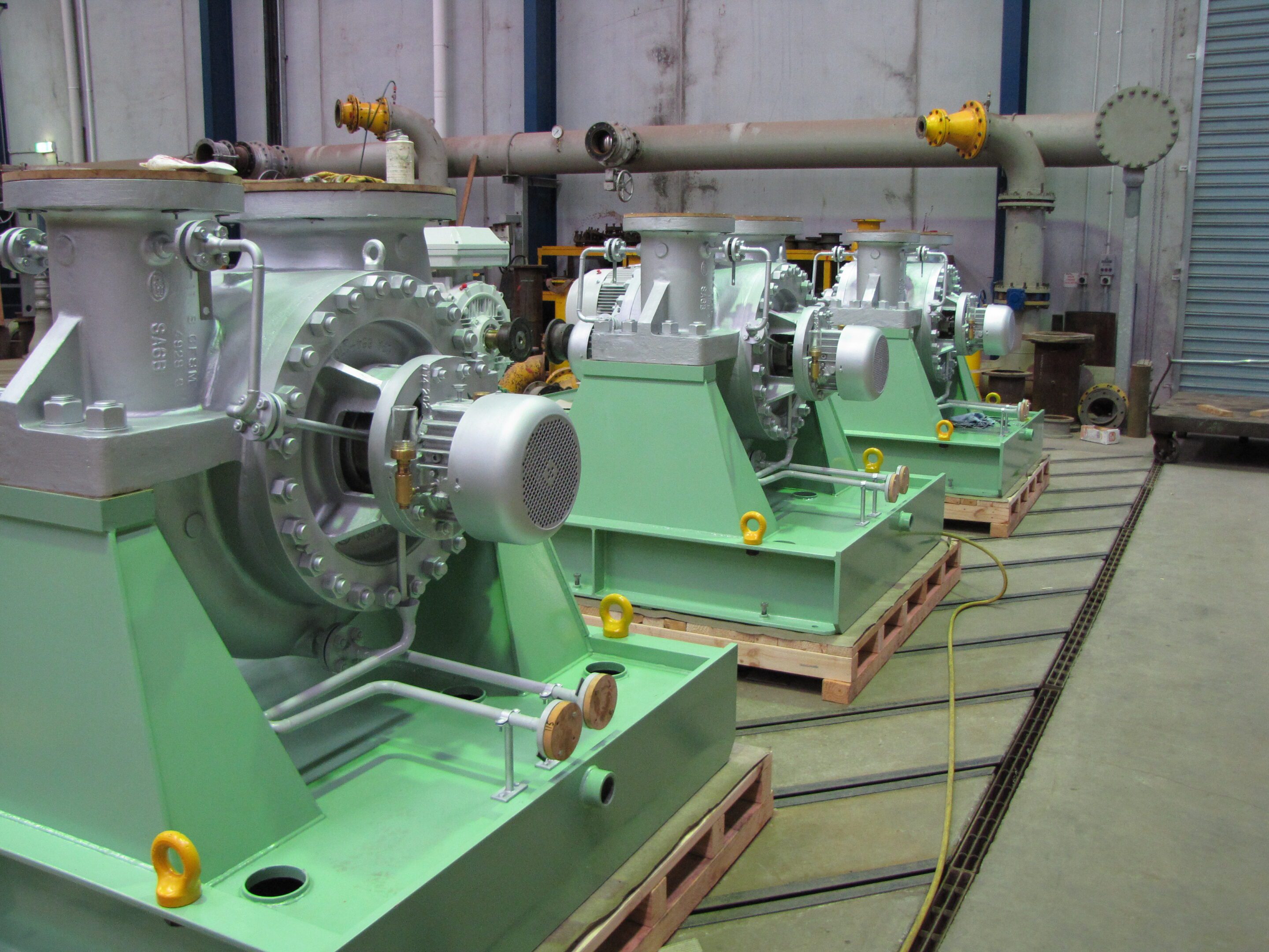 Green industrial pumps lined up in workshop