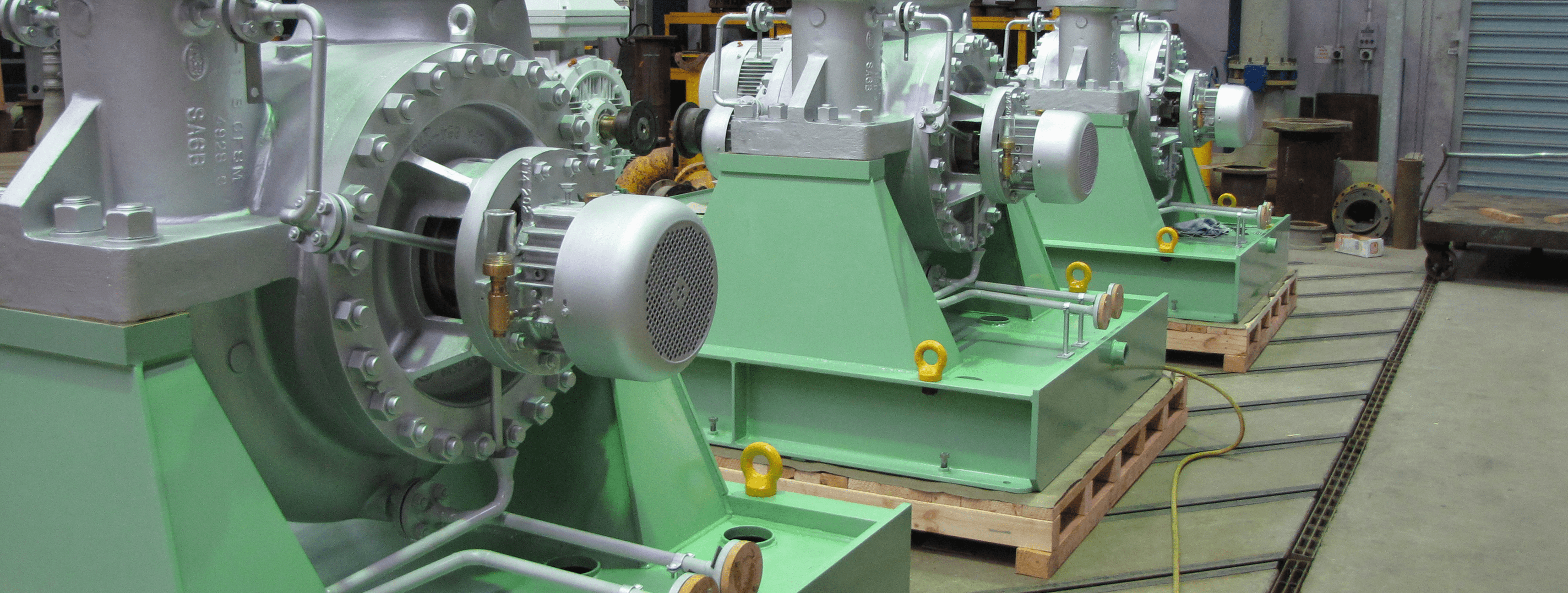 Green industrial pumps mounted on bases in factory